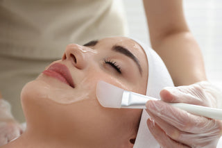 Woman receiving a chemical peel treatment with a brush by an esthetician
