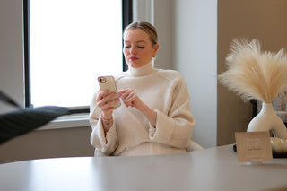 Skin Devotee founder answering a client message from her phone, sitting in Skin Devotee lobby 