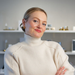 Skin Devotee Founder and Esthetician, Joanna Kula standing inside Skin Devotee Facial Studio with blurred retail background 