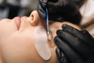 A lash lifting service being performed on a woman's eye lashes to help lift the eye lashes so that it remains lifted throughout the day.