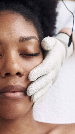 Black woman getting a lifting and sculpting facial with microcurrent gloves at Skin Devotee Facial Studio in Philadelphia