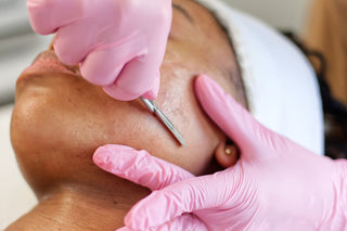 Young genz woman, receiving a dermaplaning treatment by her esthetician at Skin Devotee Facial Studio
