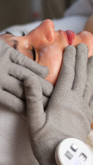 woman receiving a  signature treatment at Skin Devotee Facial Studio using microcurrent gloves