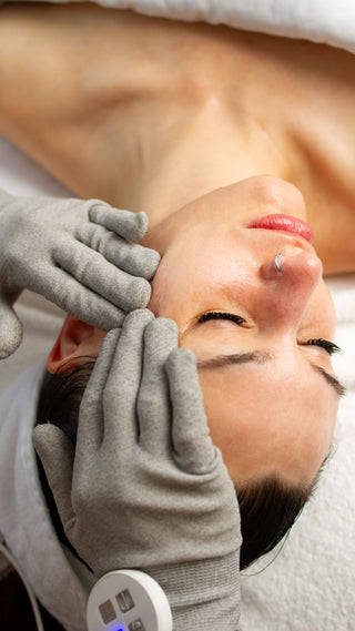 woman receiving a  signature treatment at Skin Devotee Facial Studio using microcurrent gloves