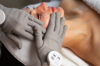 woman receiving a  signature treatment at Skin Devotee Facial Studio using microcurrent gloves