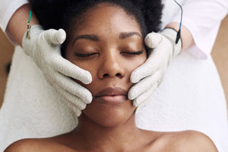 Black woman getting a lifting and sculpting facial with microcurrent gloves at Skin Devotee Facial Studio in Philadelphia
