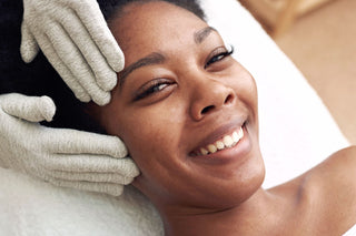 Smiling black woman receving a microcurrent treatment at Skin Devotee Facial Studio in Philadelphia