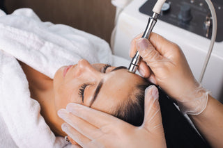 Woman receiving a microdermabrasion treatment during a facial by an esthetician